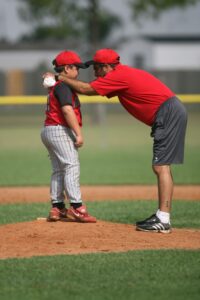 Coach talking to young pitcher on the mound during pitcher lessons